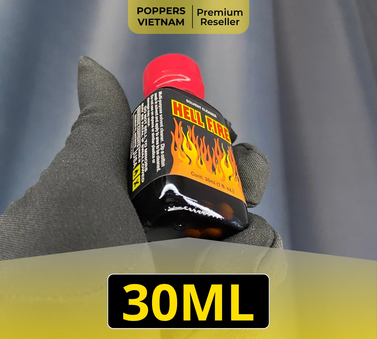 Chai popper Hell Fire 30ml màu chủ đạo là đen và pha thêm chút đỏ. Sản phẩm sắc nét được cầm bằng găng tay xám với phông nền đen.