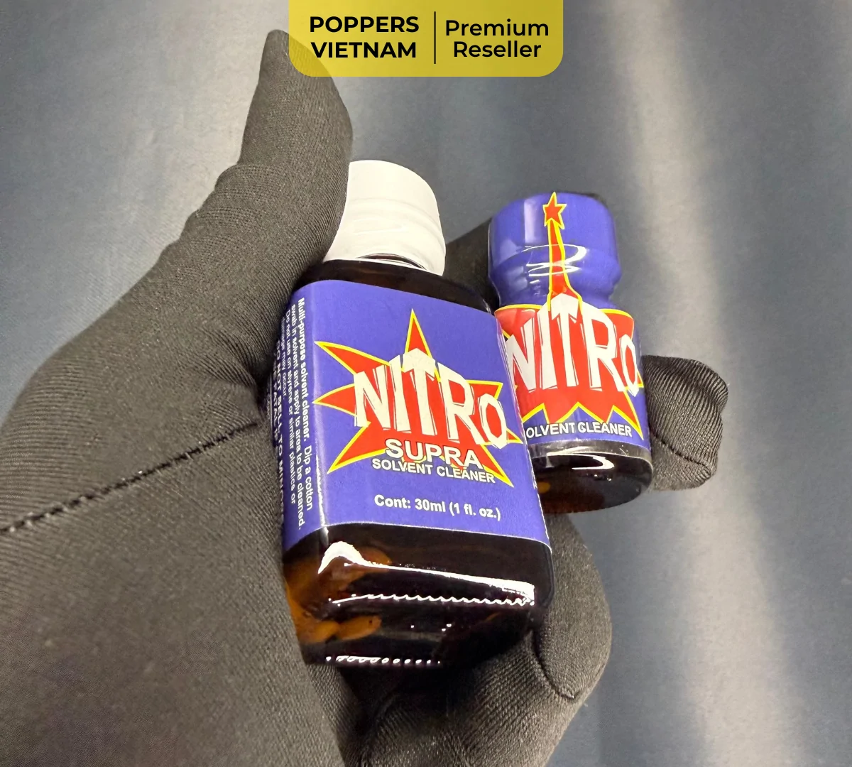 Hình ảnh cận cảnh 2 chai poppers Nitro với dung tích 10ml và 30ml được cầm tay bao tay vải, nền phía sau màu đen. Sản phẩm được Poppers Việt Nam chụp độc quyền bằng máy ảnh kỹ thuật số với độ phân giải cao, sắt nét.